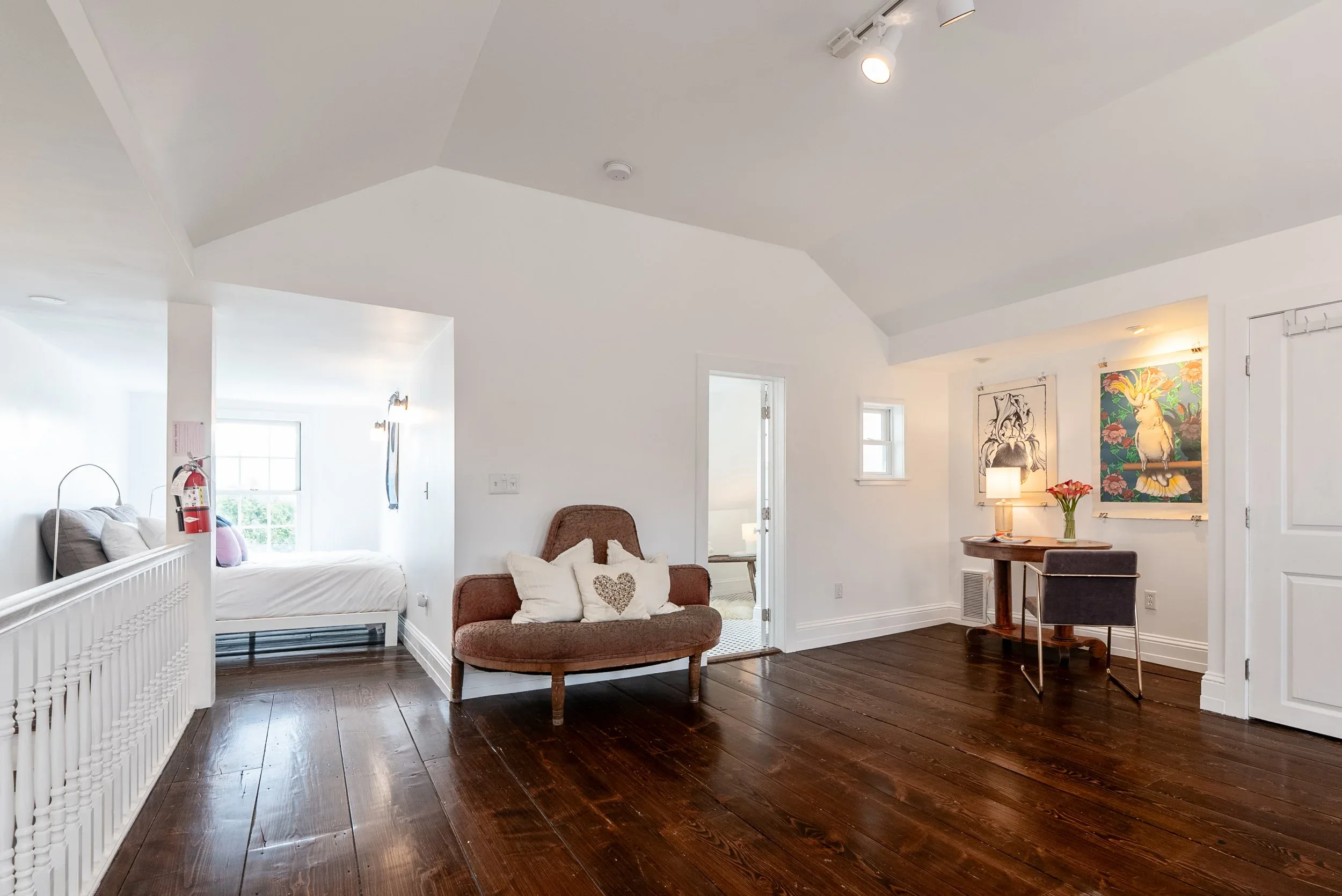 Airy bedroom with a queen bed, tall windows, and eclectic collected artwork on the walls
